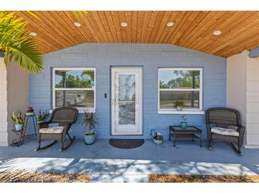 Inviting front porch with comfortable seating, two windows and charming decor at 1344 Dartmouth Dr, Holiday, FL 34691