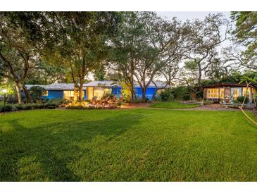 Expansive green lawn view featuring a charming home and inviting outdoor seating area amid mature trees at 1880 Belleair Rd, Clearwater, FL 33764