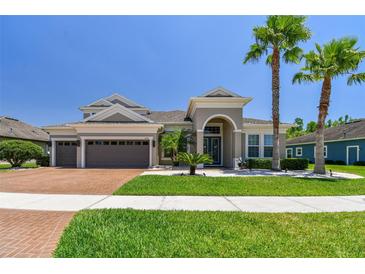 Charming home featuring a three-car garage, manicured lawn, and elegant landscaping at 32791 Natural Bridge Rd, Wesley Chapel, FL 33543