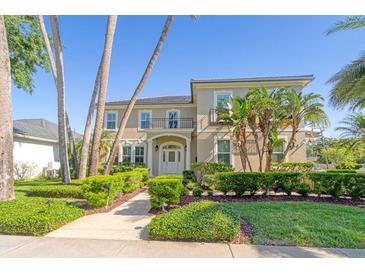 Two-story home featuring manicured landscaping, palm trees and a second story balcony on a sunny day at 4301 W Swann Ave, Tampa, FL 33609
