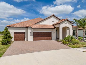 Charming single-story home featuring a tile roof, three-car garage, and inviting front yard with manicured landscaping at 5329 Windy Grove Dr, Wimauma, FL 33598