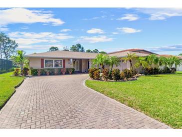 Charming home featuring a brick driveway, lush landscaping, and well-maintained lawn at 6790 Burning Tree Dr, Seminole, FL 33777