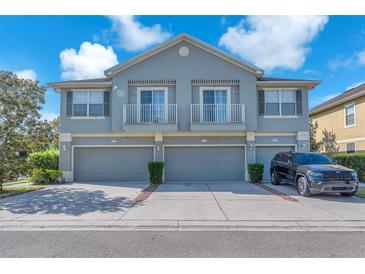 Two-story townhome featuring gray exterior, a pair of balconies, three garage doors, and well-maintained landscaping at 6851 Breezy Palm Dr, Riverview, FL 33578