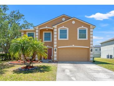 Charming two-story home featuring an attached garage and a well-manicured lawn with vibrant landscaping at 7102 W Creek Dr, Tampa, FL 33615