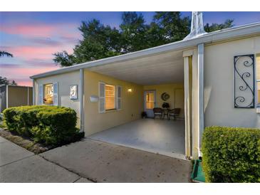 Charming home featuring a covered carport with seating and manicured landscaping, offering a warm and inviting curb appeal at 854 Sky Loch N Dr, Dunedin, FL 34698