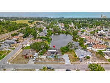Stunning aerial view of the property with a beautiful pond and mature trees in a serene neighborhood setting at 1023 Springtime Dr, Holiday, FL 34691