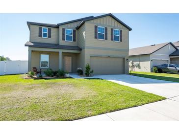 Two-story home featuring a well-kept lawn, two-car garage, and neutral-toned exterior at 35853 Buttonweed Trl, Zephyrhills, FL 33541