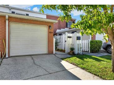 Charming brick home with attached garage and landscaped walkway to gated entrance at 404 Danube Ave, Tampa, FL 33606