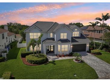 Elegant two-story home with lush lawn, manicured landscaping and paver driveway at 750 Sand Pine Ne Dr, St Petersburg, FL 33703