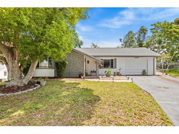 Charming single-story home featuring stone accents, a well-manicured lawn, and an attached garage at 7714 Bayleaf Dr, Hudson, FL 34667