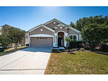 Charming single-story home with a well-manicured lawn and attached two-car garage on a sunny day at 19610 Sunset Bay Dr, Land O Lakes, FL 34638