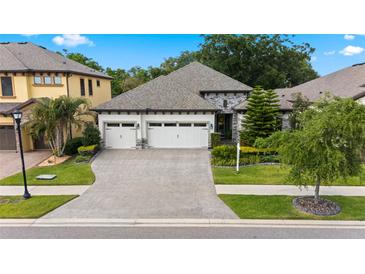 Beautiful one-story home with three-car garage, paver driveway, stone accents, and well-maintained landscaping at 922 Grand Cresta Ave, Brandon, FL 33511