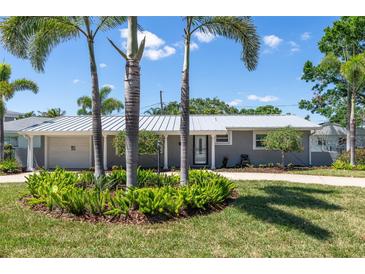 Charming single-story home with a well-manicured lawn, palm trees, and a light gray exterior paint at 1183 35Th Ne Ave, St Petersburg, FL 33704