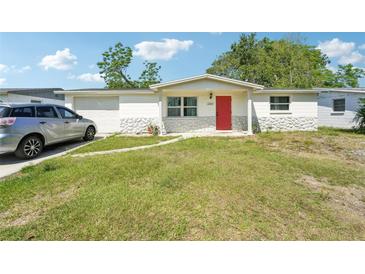Charming single-story home with a well-manicured front lawn and a vibrant red front door at 12701 Cornell Ct, Hudson, FL 34667