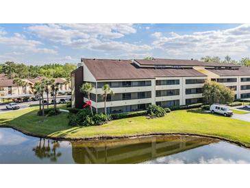 Condo complex showcasing lush landscaping, water view, and ample parking at 13610 S Village Dr # 4212, Tampa, FL 33618