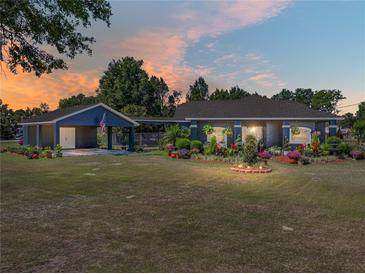 Charming single-story home with beautiful landscaping, including colorful flower beds and a spacious front yard at 14721 Scharber Rd, Dade City, FL 33525
