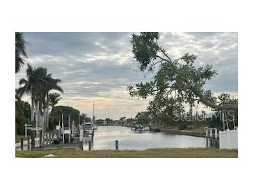 Scenic waterfront view with boat docks and tropical vegetation under a cloudy sky at 21811 Edgewater Dr, Port Charlotte, FL 33952