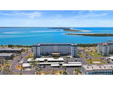 Stunning aerial view of a waterfront condo with beautiful blue water and sandy beach in the background at 7 Elgin Pl # 510, Dunedin, FL 34698