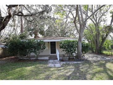Charming single-story home featuring a quaint front porch and lush, mature trees in a serene setting at 7932 Palatine Dr, Hudson, FL 34667