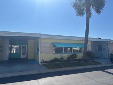 Charming single-story home with yellow paint, turquoise awning, and mature palm tree at 250 Rosery Nw Rd # 295, Largo, FL 33770