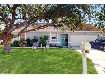 Charming single-story home with a beautiful lawn, mature tree, and a welcoming turquoise front door at 3238 6Th W Ave, Palmetto, FL 34221