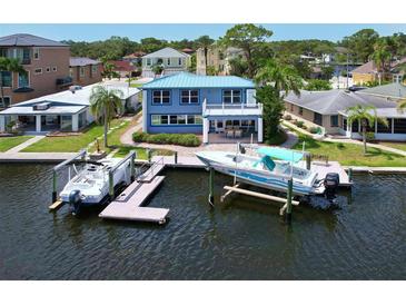 Waterfront home featuring a private dock, two boat lifts, and beautiful blue siding with a matching metal roof at 5449 Manatee Point Dr, New Port Richey, FL 34652