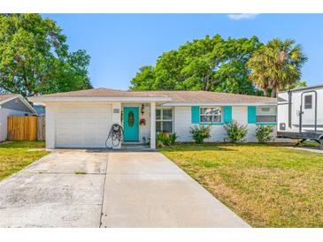 Inviting home exterior with a turquoise front door, matching shutters, and a well-kept yard at 9086 Enchantment Dr, Largo, FL 33773