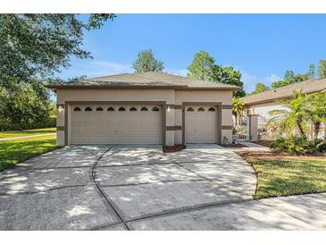 Beige two-car garage with a wide driveway and decorative doors, located in a sunny, landscaped neighborhood at 7519 Berna Ln, Land O Lakes, FL 34637
