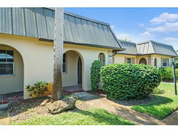 Charming villa featuring arched entryways, verdant landscaping, and a metal roof at 4144 Hampton Dr # C, New Port Richey, FL 34652