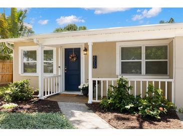 Charming home featuring a vibrant blue door and covered front porch, with lush landscaping at 4519 S Grady Ave, Tampa, FL 33611