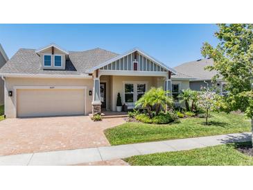 Inviting single-story home featuring manicured landscaping and a brick driveway leading to an attached two-car garage at 16677 Vibrato Ln, Land O Lakes, FL 34638
