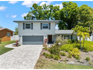 Well-maintained two-story home with a paved driveway, lush landscaping, and a gray garage door at 2525 Madrid S Way, St Petersburg, FL 33712
