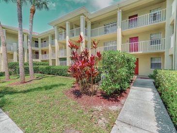 Well-maintained condo building featuring multiple balconies, mature landscaping, and vibrant red door accents at 2690 Coral Landings Blvd # 122, Palm Harbor, FL 34684
