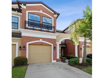 Beautiful two-story townhome with tan stucco, a garage, and a small black wrought iron balcony at 11548 Crowned Sparrow Ln, Tampa, FL 33626