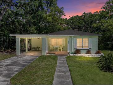 Charming single-story home with a carport, front porch with chairs, and well-maintained lawn at sunset at 131 Oak Park Ave, Brooksville, FL 34601