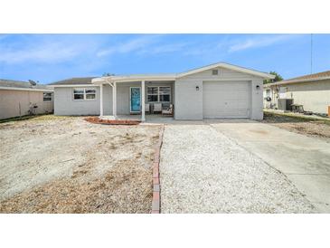 Charming single-story home features a white gravel driveway, light grey exterior and a cozy front porch at 3422 Trask Dr, Holiday, FL 34691