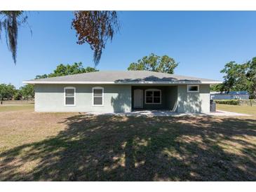 Back of home features a covered lanai with two windows and a door, plus mature landscaping at 4416 Tevalo Dr, Valrico, FL 33596