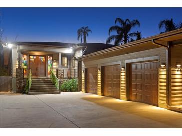 Inviting home exterior showcasing a three-car garage, landscaped entryway, and charming stone accents at twilight at 7508 N Ola Ave, Tampa, FL 33604