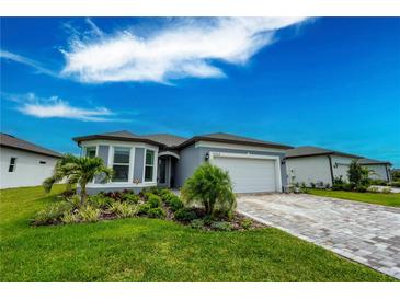 Charming one-story home with a two car garage, brick paver driveway, lush landscaping, and a well maintained lawn at 9263 Barrier Coast Trl, Parrish, FL 34219