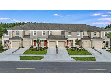 A row of beautiful townhomes with gray roofs and matching garages with landscaping along the driveways at 2204 Paravane Way, Wesley Chapel, FL 33543