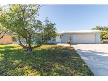 Charming home featuring a well-maintained lawn, mature tree, and a two-car garage at 22465 Lewiston Ave, Port Charlotte, FL 33952