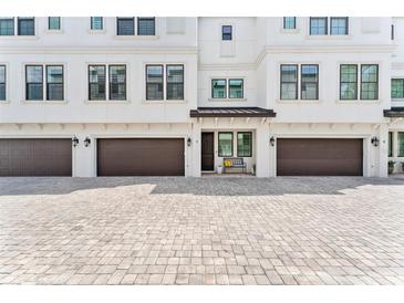 Charming townhome exterior features a brown garage door and light colored brick paver driveway at 310 S Habana Ave # 5, Tampa, FL 33609
