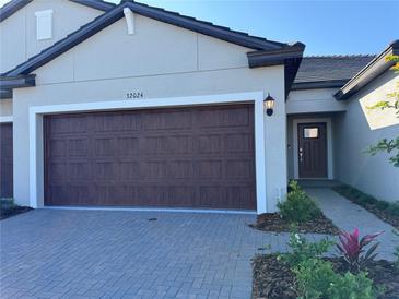 Charming home exterior with a brick driveway, two-car garage, and a welcoming front door at 32024 Griffin Sands Ln, San Antonio, FL 33576