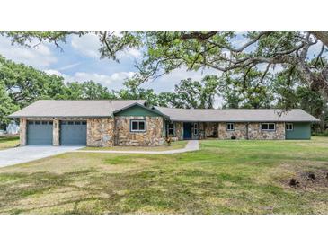 Charming stone home featuring an attached two-car garage and a well-manicured lawn at 6702 Towhe Dr, Seffner, FL 33584