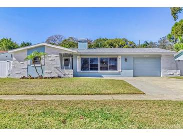 Charming single-story home featuring a well-manicured lawn, and a light blue exterior color scheme at 1560 Simmons Dr, Clearwater, FL 33756