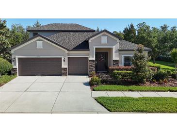 Charming two-story home featuring a well-manicured lawn, a three-car garage, and stone accents at 15625 Hawks Crest Loop, Odessa, FL 33556