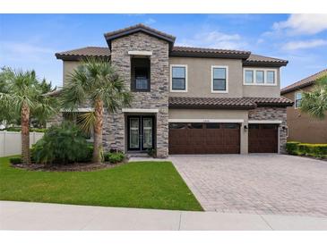 Elegant two-story home featuring stone accents, a three-car garage, a tile roof and a well manicured lawn at 21878 Amelia Rose Way, Land O Lakes, FL 34637