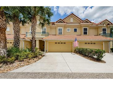 Inviting townhome with a two-car garage, tropical landscaping, and an attractive tile roof at 2674 Tanglewood Trl, Palm Harbor, FL 34685
