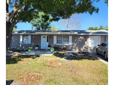 Charming single-story home with a well-maintained front yard and mature shade tree at 3304 Williamsburg Loop, Holiday, FL 34691