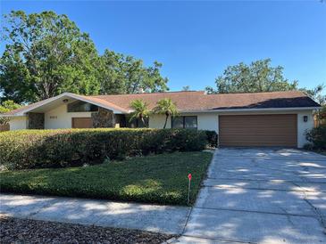 Charming single-story home with a well-kept lawn, a two-car garage, and stone architectural details at 6703 Peachtree Dr, Temple Terrace, FL 33617